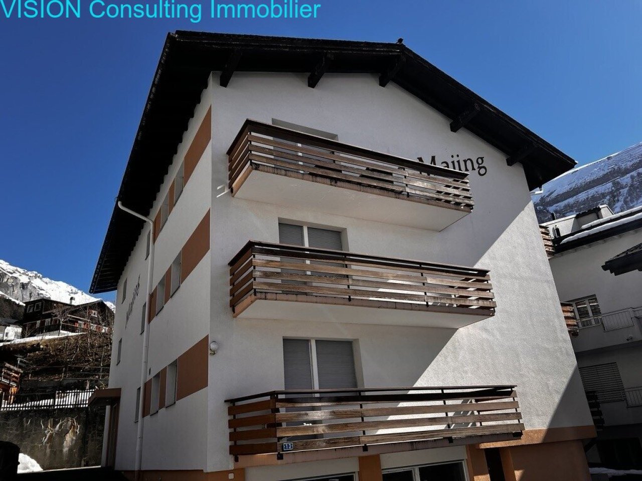 Modernes Mehrfamilienhaus mit durchdachter Balkonarchitektur und alpinem Standort